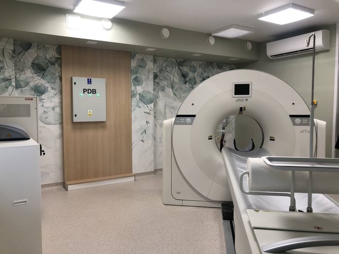 The CT scanner in place; the electrical distribution board on the wall, with a radiation-shielded door beside it.
