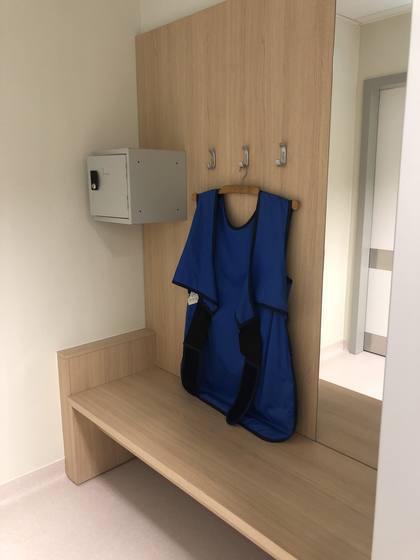 Lead apron holders on wall hooks, with a bench underneath.
