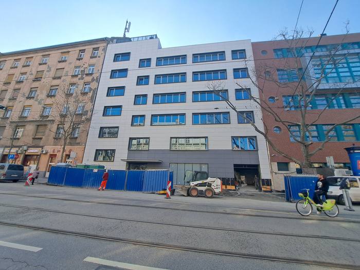 The street facade during construction, with the site hoarding.